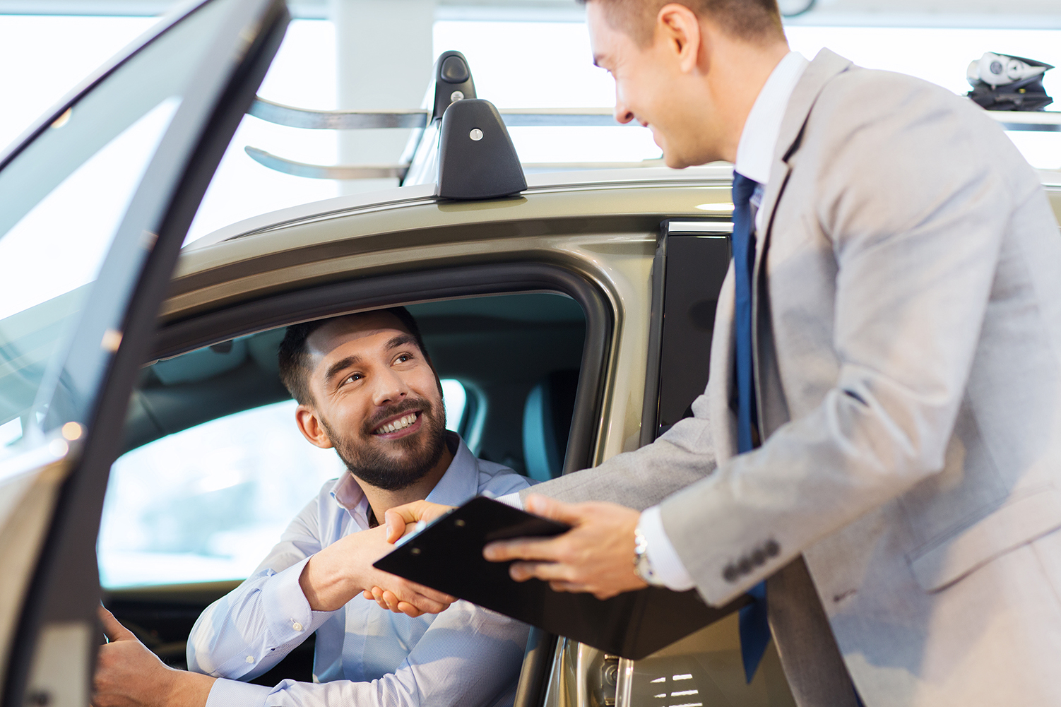 man in new car shaking hand of seller